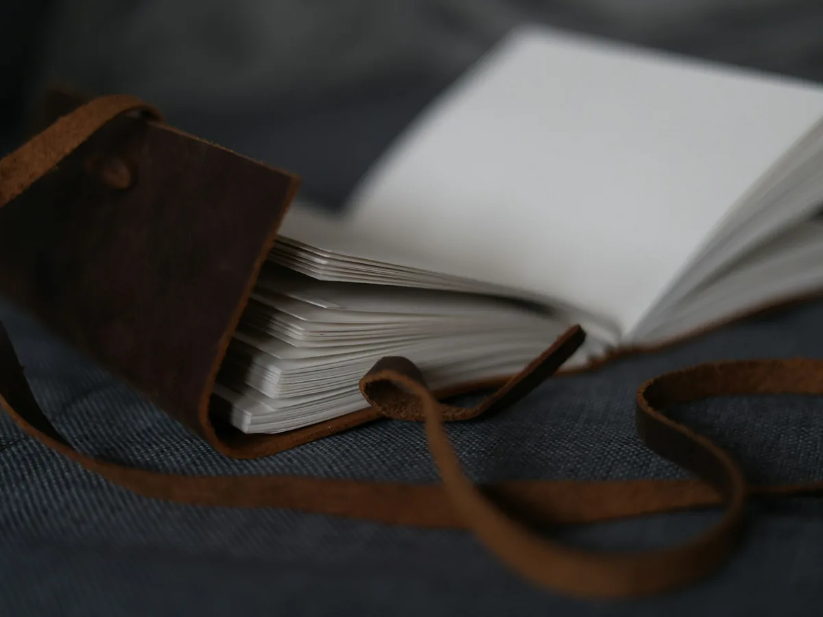Open brown leather journal with blank pages and a wraparound leather tie.